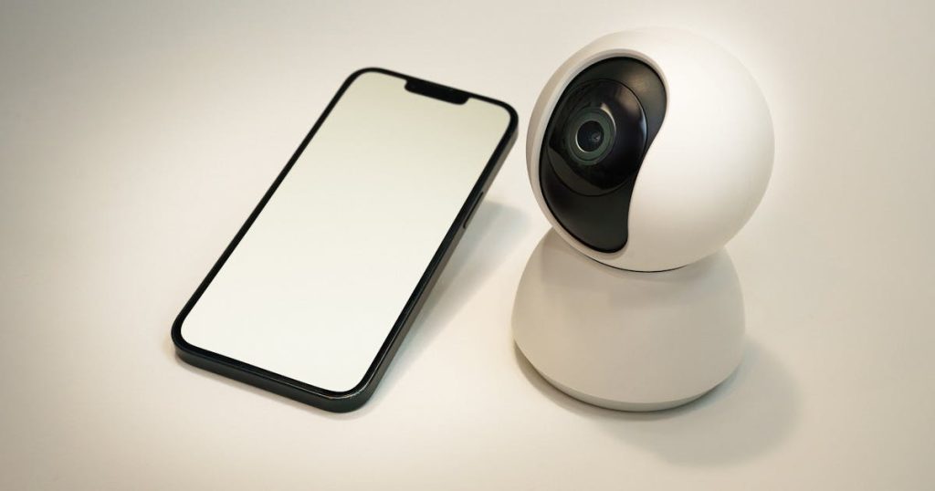 Caméra de surveillance connectée avec smartphone affichant un flux vidéo cloud