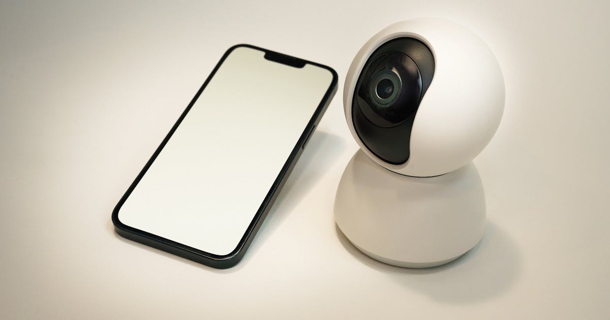 Caméra de surveillance connectée avec smartphone affichant un flux vidéo cloud
